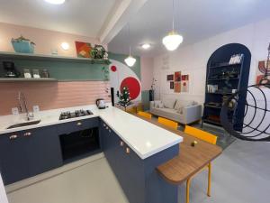 a kitchen with blue cabinets and a living room at Incrível apto com banheira e garagem perto de tudo in Florianópolis