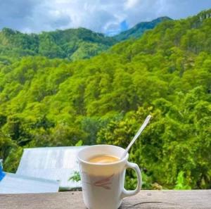 a cup of coffee with a spoon sitting on a table at Joan's All Seasons Homestay in Taccon