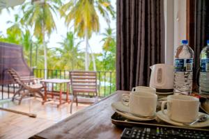 a wooden table with two cups and a keyboard and water bottles at Lake Edge Resort in Hambantota