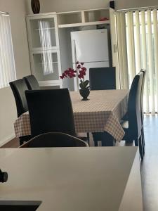 a dining room table and chairs with a table and flowers at Lidcombe Olympic Park Dudley in Auburn