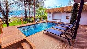 a swimming pool on a wooden deck with two chairs at Shore of Sapanca Lake Çatı Villa Lakehouse in Kartepe