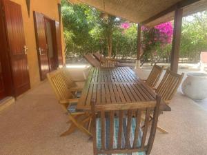 a wooden table and chairs on a patio at Superbe villa avec piscine privée à 500m de la plage à Nianing in Nianing