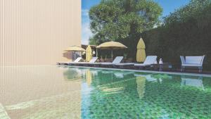 a swimming pool with lounge chairs and umbrellas at The Loft Mirissa in Mirissa