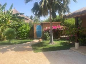 a garden with a palm tree and a house at Superbe villa avec piscine privée à 500m de la plage à Nianing in Nianing