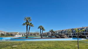 a pool with palm trees in front of a building at Panoràmic Vinaros in Sant Jordi