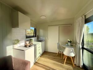 a kitchen with a sink and a table in it at Benrose Stables Cottage in Palmerston North +3 photos