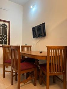 a wooden table with chairs and a television on a wall at Neon Villa in Pondicherry