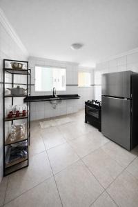 a large kitchen with a stainless steel refrigerator at Apê 202 - Central, Garagem e Ar Cond - 2Q e 2B in Governador Valadares