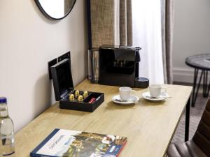 a table with a box of fruit and two coffee cups at Mercure Oxford Hawkwell House Hotel in Oxford +94 photos