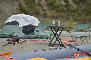 a table and chairs and a tent on the beach at Wild Camping Vjosa in Përmet