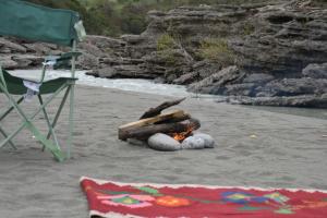 a campfire on a beach next to a chair at Wild Camping Vjosa in Përmet