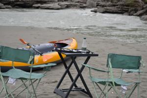 a table and two chairs and a boat on the beach at Wild Camping Vjosa in Përmet