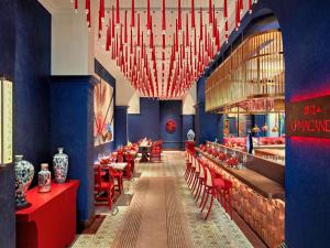 a restaurant with red tables and chairs and chandeliers at Mövenpick Hotel Hanoi Centre in Hanoi