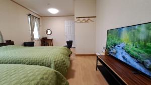 a bedroom with two beds and a large flat screen tv at ホリデーハウス慈野(ジノ) in Takayama