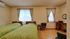 a bedroom with two beds and a desk with a chair at ホリデーハウス慈野(ジノ) in Takayama