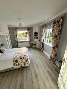 a bedroom with a large bed and two windows at Big Pop's House in Kilmacthomas