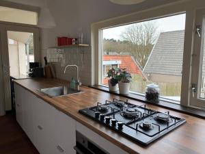 a kitchen with a stove and a sink and a window at Kust Geluk in Schoorl