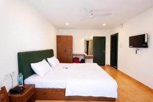 a bedroom with a white bed and a flat screen tv at Hotel Maharaja in Rewa