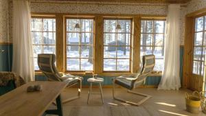 a living room with a table and chairs and windows at Sunshine Stuga Mörtsjön in Stugun