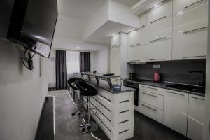 a kitchen with white cabinets and a black counter at Apartman Lena lux in Vrnjačka Banja