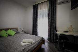 a bedroom with a bed with green pillows and a desk at Apartman Lena lux in Vrnjačka Banja
