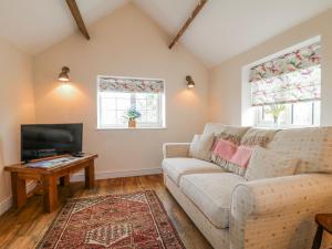 a living room with a couch and a tv at The Granary Barn at America Lodge in Oakham