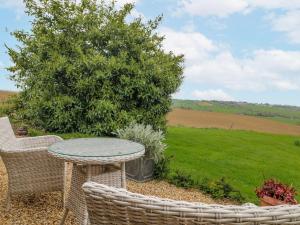 a patio with a table and chairs and a field at The Granary Barn at America Lodge in Oakham