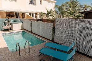 a swimming pool with two blue chairs and a house at Toma Villa in Paralimni