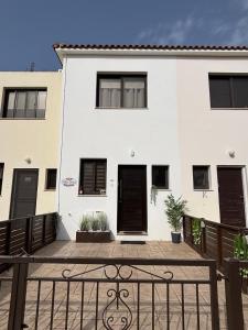 a white house with black doors and a fence at Toma Villa in Paralimni