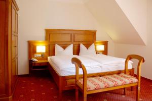 
a hotel room with a bed, chair, and nightstand at Hotel Wasserschloss Mellenthin in Mellenthin

