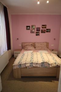 a bedroom with a bed with a pink wall at Szántó Villa in Hévíz