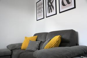 a gray couch with yellow pillows in a living room at Valuna - Modern Sea View Apartment -Terrace - 4 Min to Beach - Free Parking in Jadranovo
