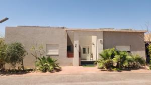 a gray house with a white door and some plants at Pure Sense in Beʼer Ora