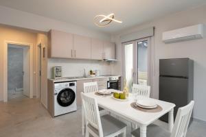 a kitchen with a white table and chairs and a kitchen with a refrigerator at Kamara View Apt 1 in Agios Nikolaos