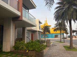a building with a palm tree next to a street at D02 - Happy Beach Villas - No2 Căn hộ Z&Z Triple key - NovaWorld Ho tram in Binh Chau