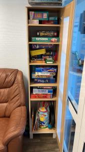 a book shelf filled with books next to a chair at Appartementhaus Ostseeresidenz in Heiligenhafen +21 photos