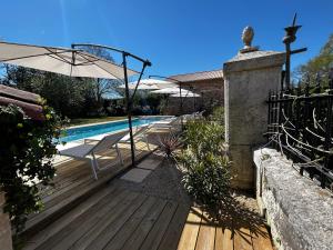 a wooden deck with an umbrella and a swimming pool at Maison La Galeze in Pouillac
