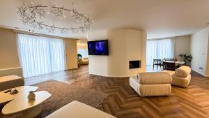 a living room with a couch and a tv on a wall at Vatër Selected Rooms in Tirana