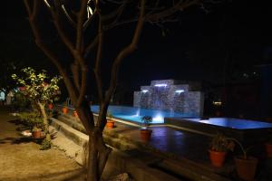 a pool at night with buildings in the background at Aspen Riverside Resort in Rishīkesh