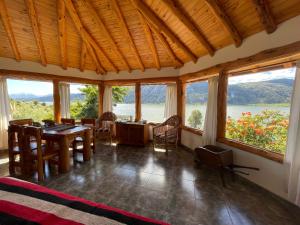 a dining room with a table and chairs and windows at Cabañas El Muelle in Cholila