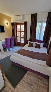 a bedroom with a large bed with purple furniture at Pansion Oscar Summer Garden in Mostar