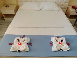 a bed with two white towels with red buttons at Elflora Otel in Ceyhan