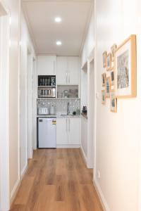 a kitchen with white cabinets and a wooden floor at The Guesthouse in Terang