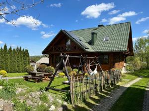 a wooden house with a playground in front of it at Agroturystyka Ranczo Turzyniec w pobliżu Zwierzyńca in Turzyniec