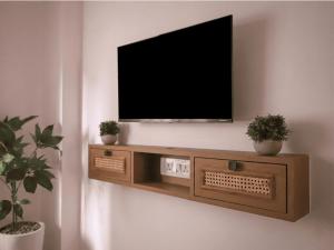 a television on a wall with two potted plants at Nivara Stays Lingampalli, A Boutique Hotel Brand in Hyderabad