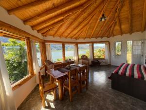 a dining room with a table and some windows at Cabañas El Muelle in Cholila