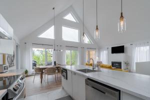 a kitchen and living room with white walls and windows at Dahlia #1 - Spa & Pets in Valcartier Station