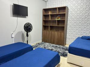a bedroom with two beds and a tv and a book shelf at Interlagos Family House in São Paulo