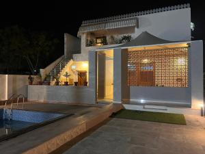 a house with a swimming pool at night at Peace The Green Heaven in Jaipur