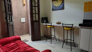 a living room with a couch and two bar stools at Funcional, cômoda e confortável in Camaçari